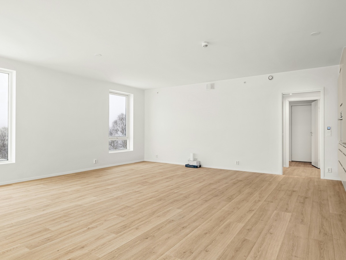 A bright, empty room with a newly installed light oak floor.
