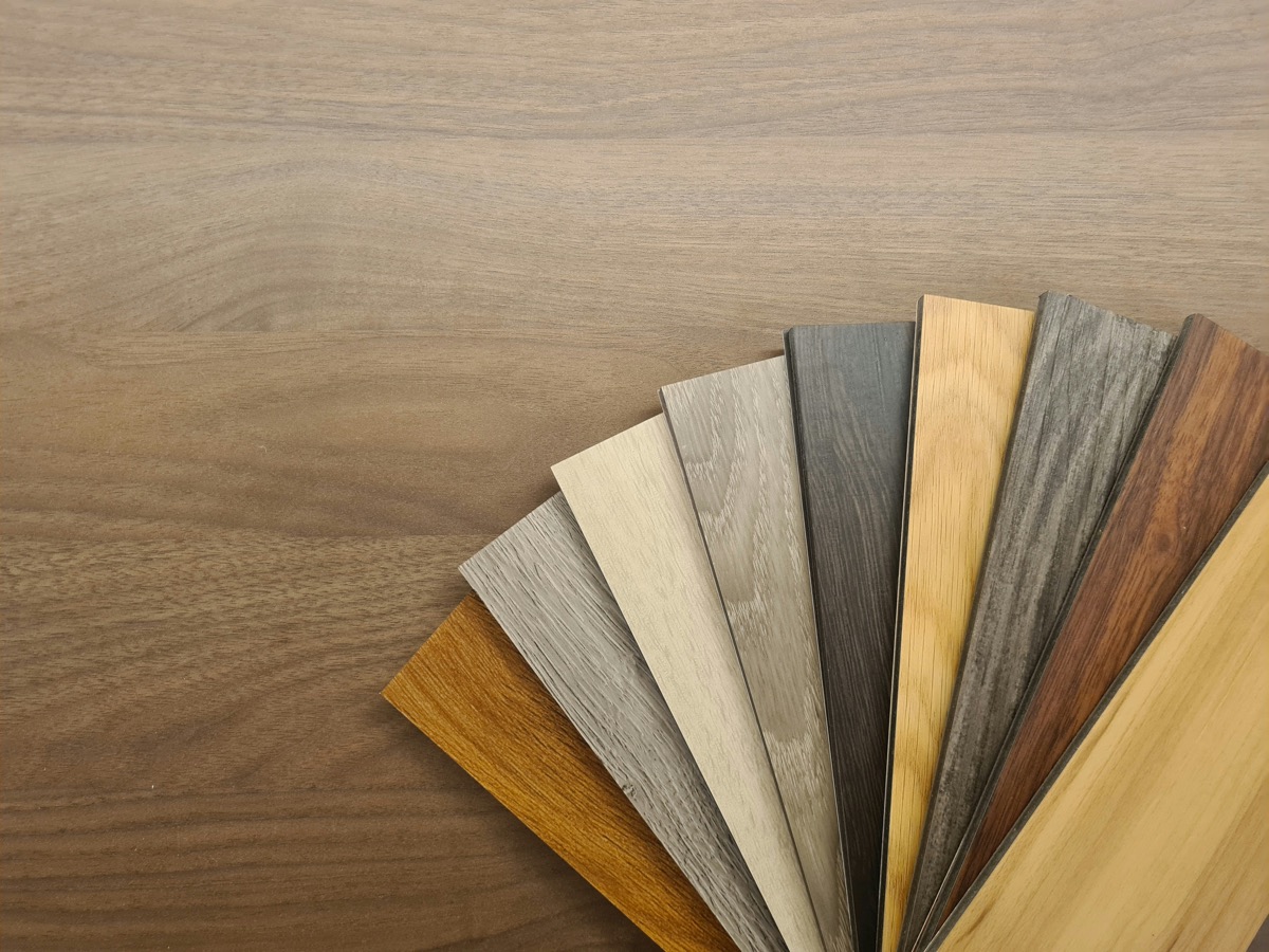 A fan of flooring plank samples in oak, grey and walnut tones.